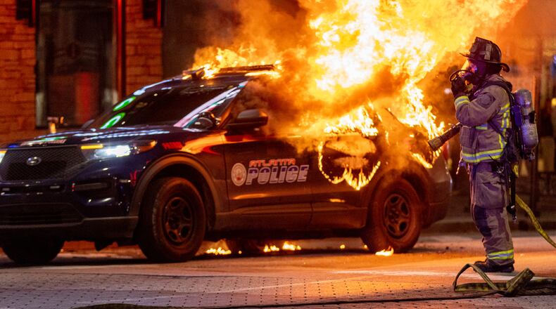 Atlanta firefighters prepared to extinguish a police car that was set afire during a Forest Defenders protest in Atlanta Saturday, Jan 21, 2023. The Atlanta Police Department said several arrests had been made. (Photo: Steve Schaefer / steve.schaefer@ajc.com)