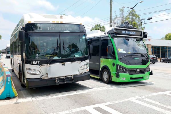 A MARTA bus and an ATL Spoke autonomous vehicle are seen as they depart from the West End MARTA Station on Monday, June 1, 2026. The ATL Spoke, an autonomous pilot program, started offering service recently. It connects the West End MARTA and the Lee + White District. It runs seven days a week. (Miguel Martinez/AJC)