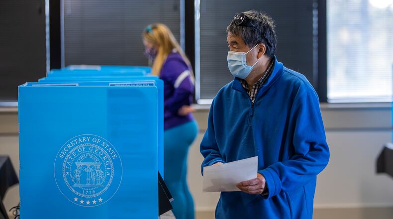 A voter participates in the first day of early voting for the Georgia US Senate runoff election at Gwinnett CountyÕs Shorty Howell Park in Duluth, Georgia, USA, 14 December 2020. Some voters may receive a confirmation notice including a form from Gwinnett County Voter Registrations and Elections. (AJC File)
