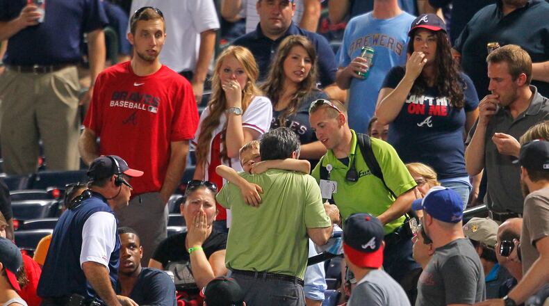 In this Tuesday, May 20, 2014 photo, fans react as a young boy is picked up by his father and rushed up the steps after being hit by a foul ball off the bat of Milwaukee Brewers' Carlos Gomez in the seventh inning of a baseball game against the Atlanta Braves in Atlanta. The 8-year-old boy who was struck in the head has been released from the hospital and is "doing well." While the family requested privacy and boy's name was not released, the Braves said Thursday they had received a call from the victim. He thanked the players who visited him in the hospital and let the team "know that he's home and doing well." (AP Photo/Todd Kirkland)