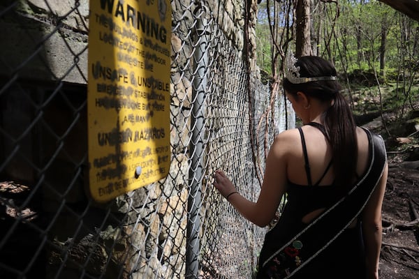 West Virginia Coal Festival teen beauty pageant winner Ava Johnson, 16, stands by a fence and sign warning visitors to keep out of the buildings and structures at the former Kay Moor coal town and camp in the New River Gorge National Park and Preserve near Fayetteville, W.Va., Thursday, April 17, 2025, (AP Photo/Leah Willingham)