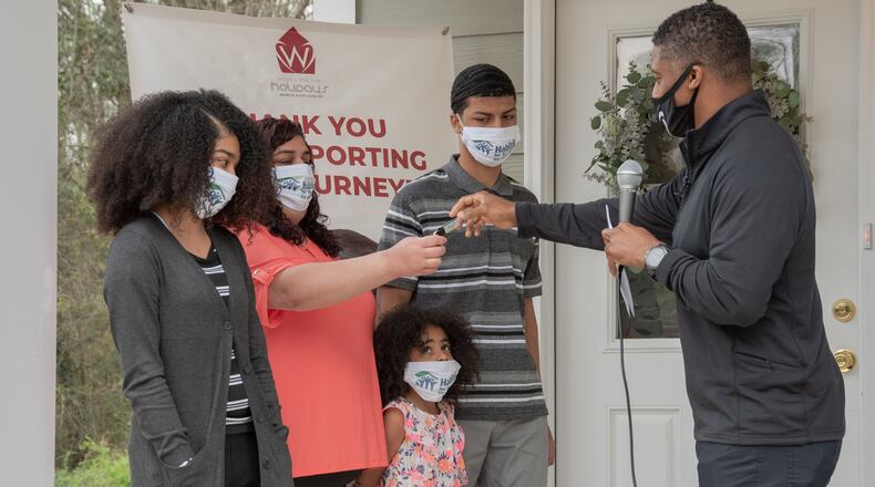 Warrick Dunn, Warrick Dunn Charities, presents a house key to new Habitat homeowner Layla Esmaili and her family.