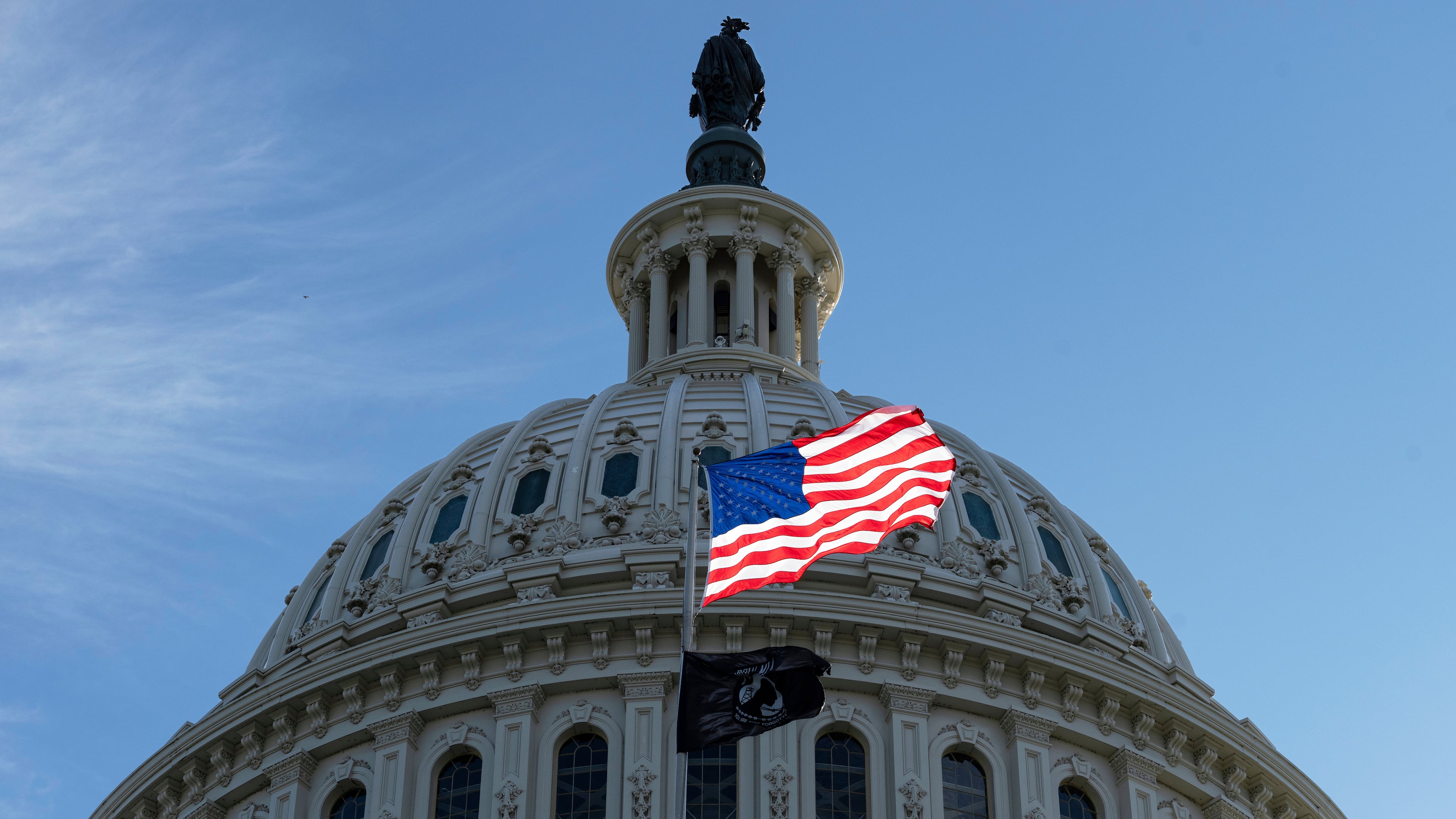 The American flag over the Capitol is illuminated by the early morning light on the first day of a government shutdown, in Washington, Wednesday, Oct. 1, 2025. (AP Photo/J. Scott Applewhite)