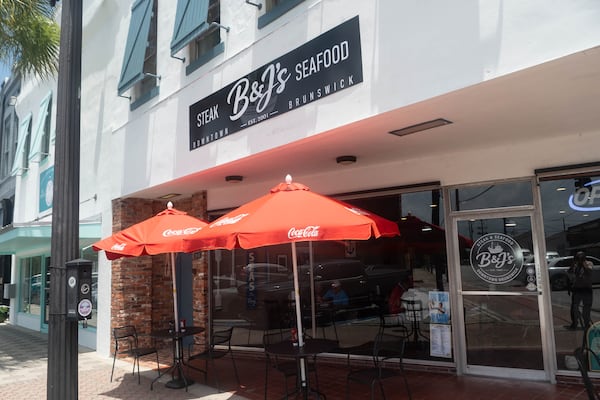 The exterior of a restaurant in downtown Brunswick with red umbrellas out front and a sign that says B&J's Steaks & Seafood.