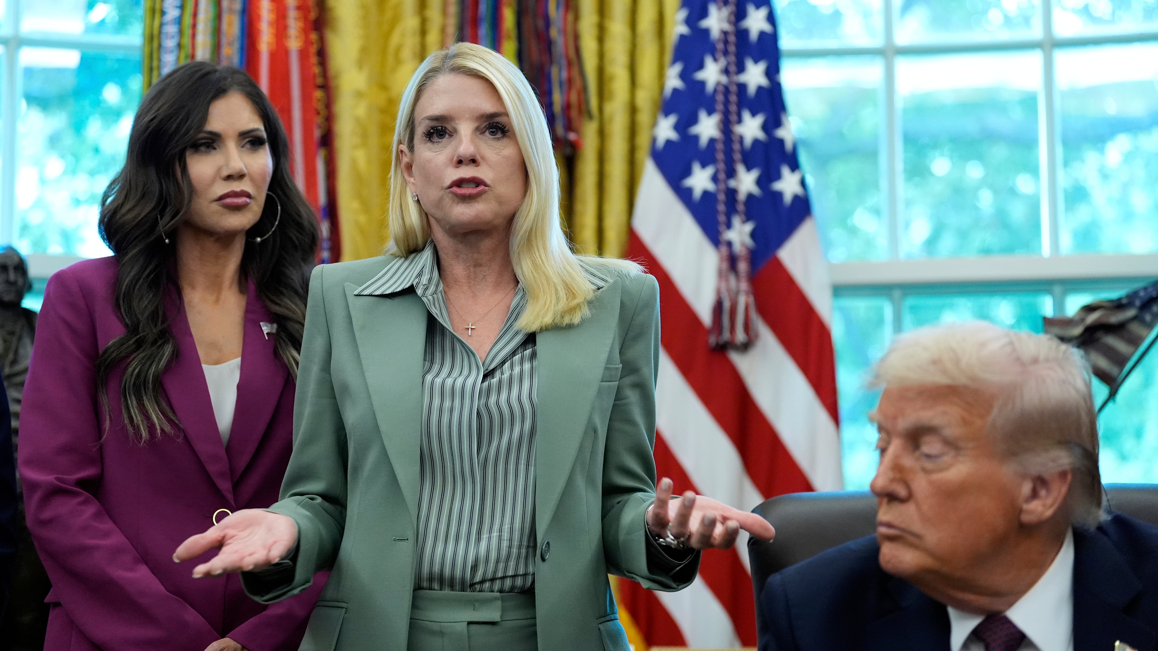 Attorney General Pam Bondi speaks as Homeland Security Secretary Kristi Noem, left, and President Donald Trump listen in the Oval Office of the White House, Monday, Sept. 15, 2025, in Washington. (AP Photo/Alex Brandon)