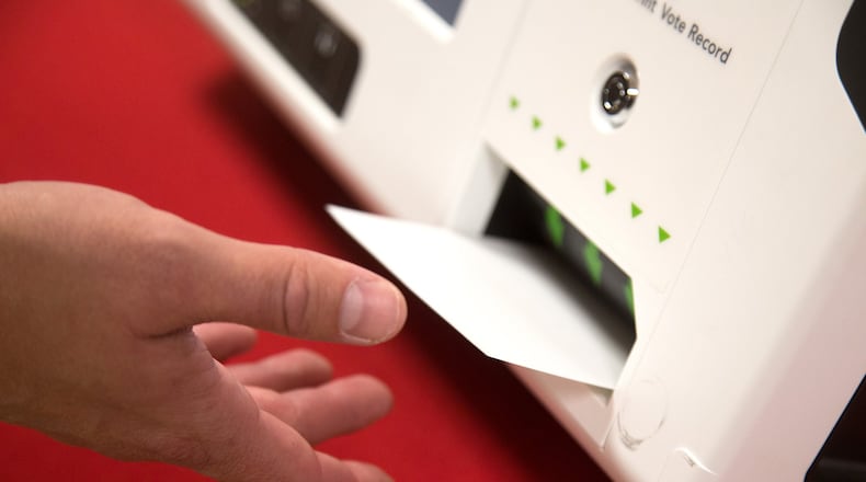 Jeb Cameron with Election Systems and Software pulls a paper ballot from a voting machine during a demonstration Tuesday at the Rockdale County Board of Elections office in Conyers. STEVE SCHAEFER / SPECIAL TO THE AJC