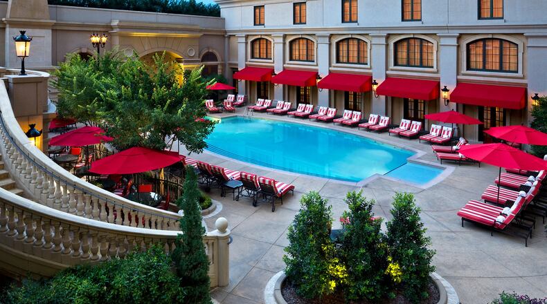The St. Regis Atlanta Pool Piazza features red-and-white lounge chairs and a dramatic cascading waterfall.