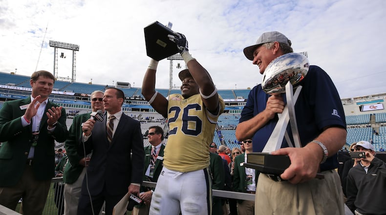 JACKSONVILLE, FL - DECEMBER 31: Dedrick Mills #26 of the Georgia Tech Yellow Jackets hoists the TaxSlayer Bowl MVP trophy as head coach Paul Johnson looks on after the game against the Kentucky Wildcats at EverBank Field on December 31, 2016 in Jacksonville, Florida. (Photo by Rob Foldy/Getty Images)