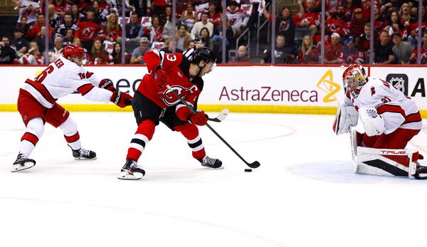 New Jersey Devils center Nico Hischier (13) scores against Carolina Hurricanes defenseman Sean Walker, left, and goaltender Frederik Andersen, right, during the first period of Game 3 of a first-round NHL hockey playoff series Friday, April 25, 2025, in Newark, N.J. (AP Photo/Noah K. Murray)