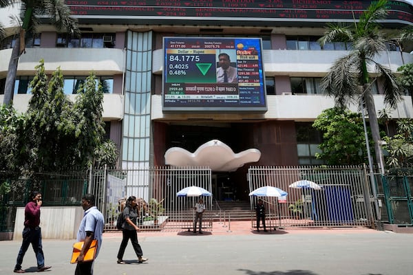 People walk past a live screen on the facade of Bombay Stock Exchange (BSE) building in Mumbai, India, Monday, May 5, 2025. (AP Photo/Rajanish Kakade)