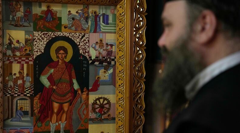 Father Nikolaos Vlavianos stands beside an icon of Saint Fanourios, known in Greek as "The Revealer," at the Church of St. Fanourios in Athens, Tuesday, Aug. 25, 2026. (AP Photo/Thanassis Stavrakis)