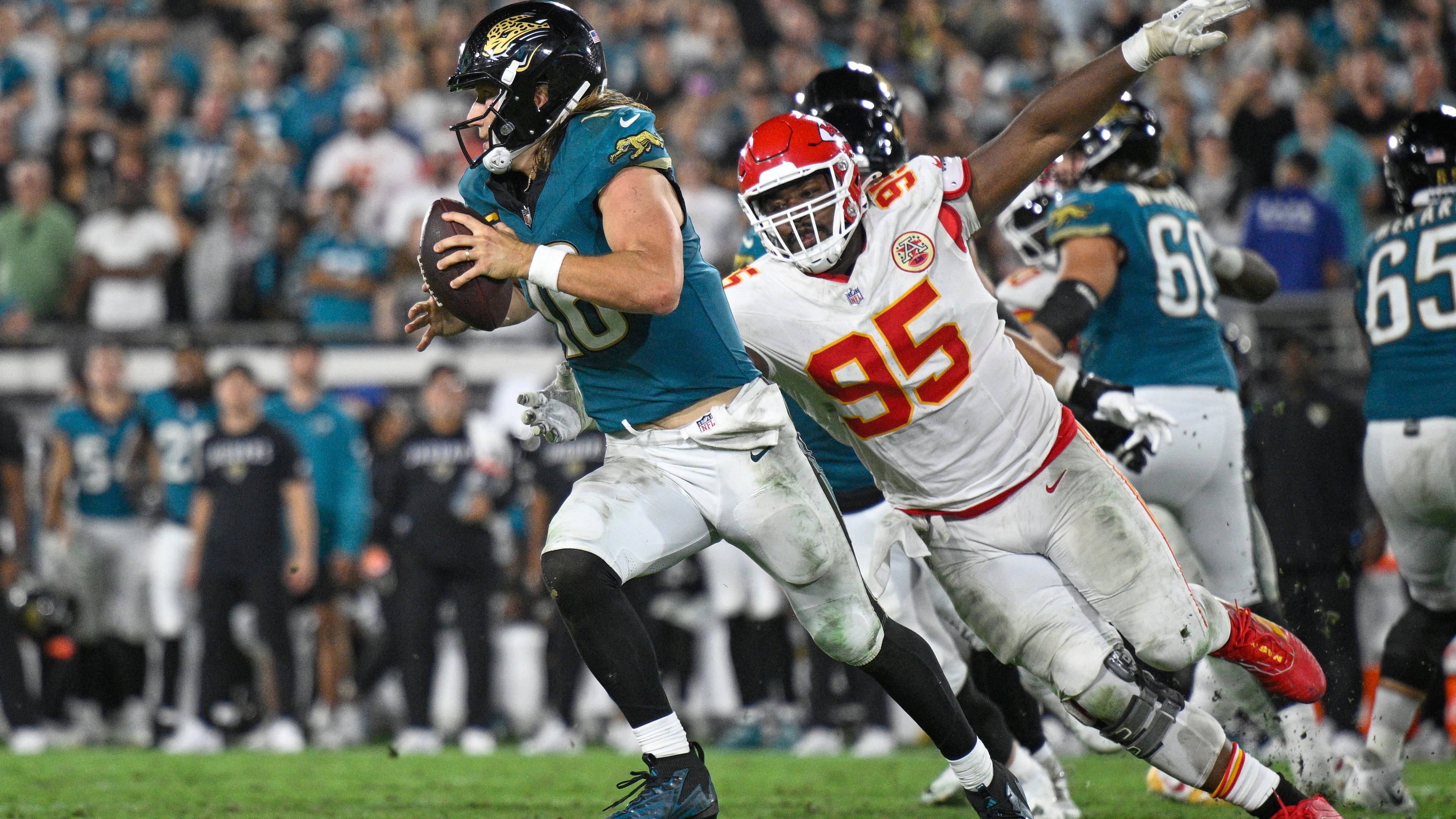 Jacksonville Jaguars quarterback Trevor Lawrence (16) gets past Kansas City Chiefs defensive tackle Chris Jones (95) as he runs the ball during the second half of an NFL football game, Monday, Oct. 6, 2025, in Jacksonville, Fla. (AP Photo/Phelan M. Ebenhack)
