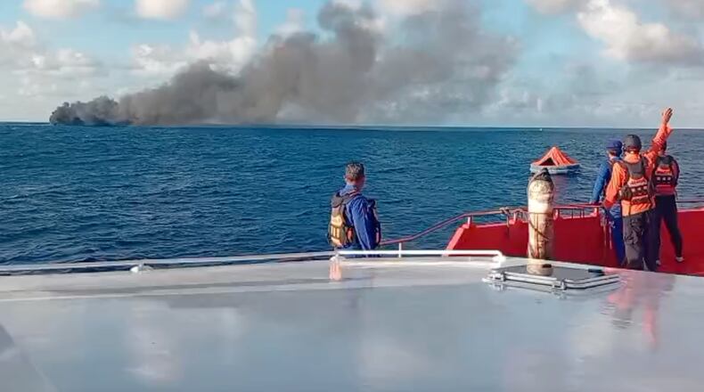In this image made from video released by the Indonesian National Search and Rescue Agency (BASARNAS), the crew of a rescue ship look on as smoke billows from a passenger ferry that caught fire while traveling from the tourist island of Bali to neighboring island of Lombok, in the waters of Lombok Strait, Indonesia, Wednesday, Aug. 12, 2026. (BASARNAS via AP)