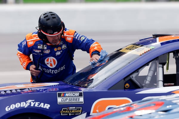 A crew member for driver Joey Logano wipes off water from the windshield during a red flag weather delay in a NASCAR Cup Series auto race, Saturday, June 28, 2025, in Hampton, Ga. (AP Photo/Butch Dill)