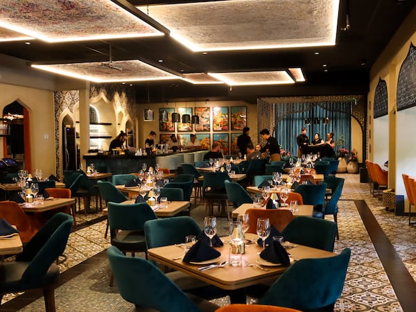 The interior of a Persian restaurant with employees setting tables.