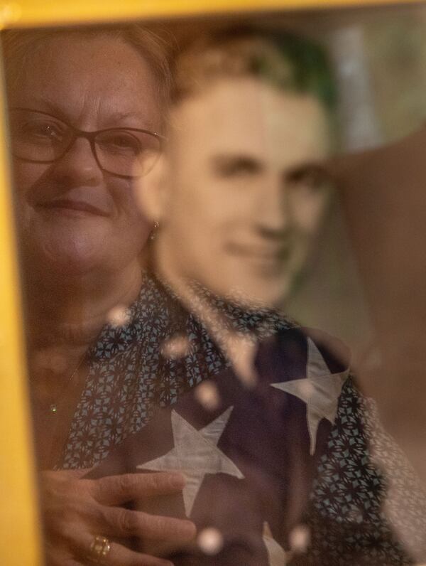 Jan Stephens is reflected in a photo of her late father, Sgt. 1st Class Lindsay Hester, who was one of nearly 100 U.S. troops who disappeared during a mission to Vietnam in 1962. (BRANDEN CAMP FOR THE ATLANTA JOURNAL-CONSTITUTION)