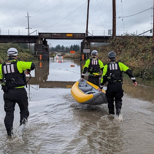 This photo provided by Snohomish Regional Fire & Rescue shows a crew using an inflatable kayak to rescue two people from a vehicle that was stranded by floodwaters, Tuesday, Dec. 9, 2025, in Snohomish, Wash. (Snohomish Regional Fire & Rescue via AP)
