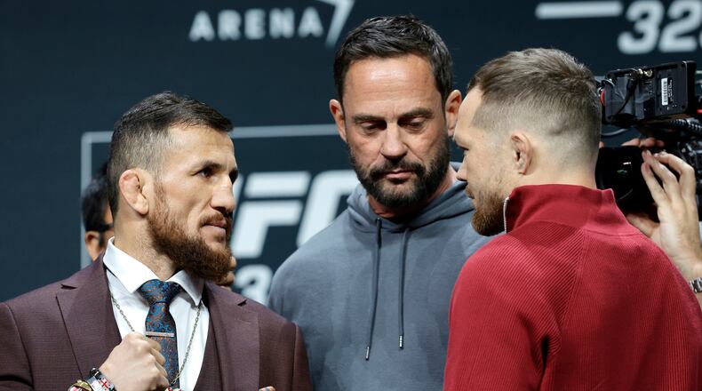 UFC bantamweight champion Merab Dvalishvili, left, of Georgia, faces off with challenger Petr Yan, of Russia, as UFC matchmaker Mick Maynard looks on during a news conference promoting UFC 323, Thursday, Dec. 4, 2025, in Las Vegas. (Steve Marcus/Las Vegas Sun via AP)