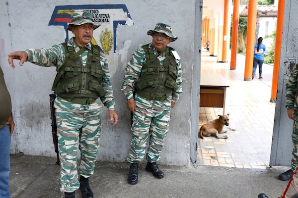 Militia members stand guard at the entrance of a polling station during a rehearsal for the upcoming regional election, in Caracas, Venezuela, Saturday, May 10, 2025. (AP Photo/Cristian Hernandez)