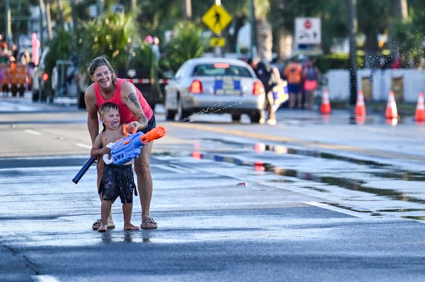 A young spectator shoots a water gun during the Tybee Beach Bum Parade, whose origin story includes softball and barstools. (Sarah Peacock for the AJC)