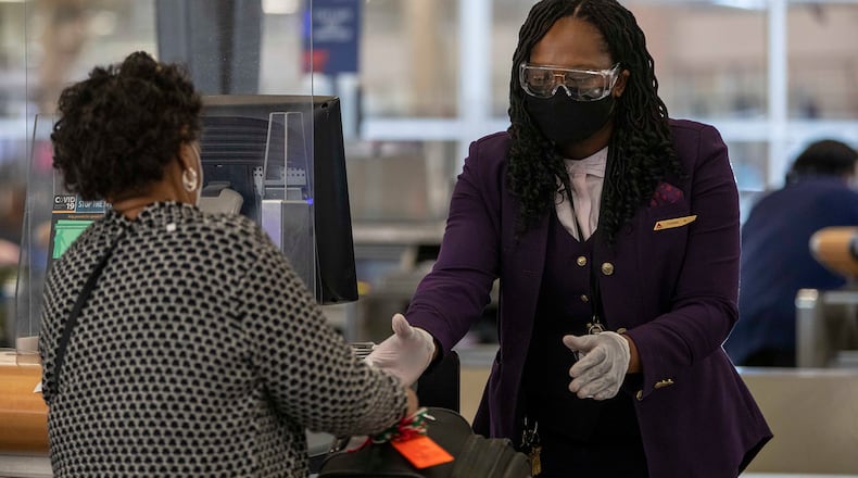 A Delta Air Lines employee handles a passenger's luggage while wearing goggle, gloves and a face mask in the domestic terminal at Hartsfield-Jackson Atlanta International Airport in Atlanta on Monday, Nov. 23, 2020. (Alyssa Pointer/Atlanta Journal-Constitution/TNS)
