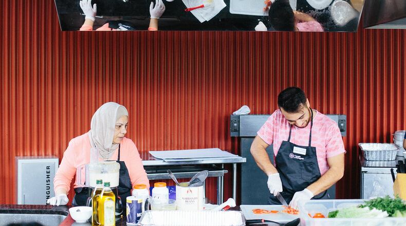Syrian chef Majeda Nakshbandi and her son Malek Alarmash of the Clarkston-based catering business Suryana Cuisine prepared hummus and tabbouleh for the crowd at the 2017 Refugee Recipe Celebration. CONTRIBUTED BY WILLIS NORMAN