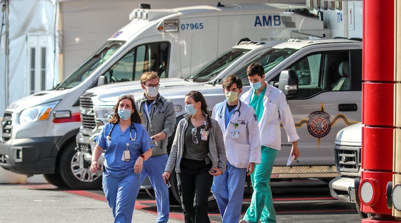 Medical workers at Grady Memorial Hospital in Atlanta emerge from the ambulance bay on Aug. 10, 2021 as Georgia hospitals are diverting emergencies because of the COVID-19 surge. Grady is only taking COVID patients. (John Spink / John.Spink@ajc.com)