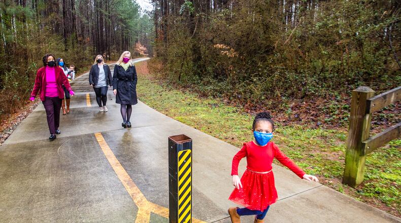 Blackwell film studio has traded land with DeKalb County making way for a new park with a splash pad, security, playgrounds and outdoor space for the Bouldercrest community.  Neighborhood leaders, including Pat Culp, from left, the Clark family (Demi, 3, front; mother Alison, 7-month-old Lucas), Sarah Cotten and Ingrid Buxbaum walk a path that will soon be part of the film studio Friday, Feb 12, 2021. A mile away, ground has been broken for the new DeKalb park.   (Jenni Girtman for The Atlanta Journal-Constitution)