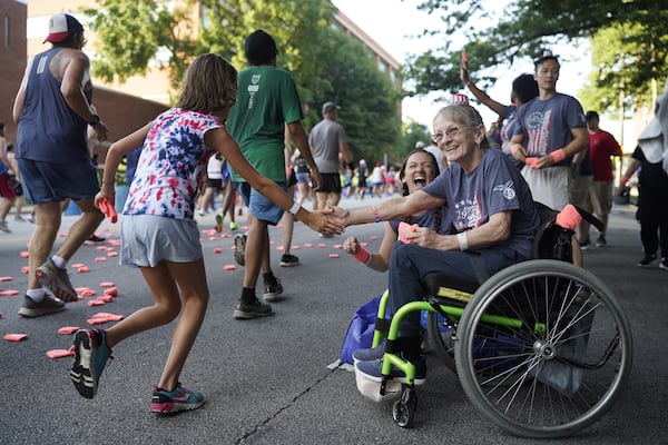 Patient at the Shepherd Center welcomes runners on Cardiac Hill along Peachtree Street during the 55th running of the Atlanta Journal-Constitution Peachtree Road Race in Atlanta on Thursday, July 4, 2024.   (Seeger Gray / AJC)
