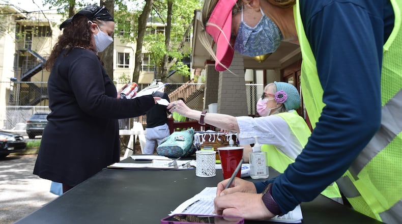 Volunteers Jodi Lewis Lipsitz and Stefanie Agusta (right) help a client with checking in for COVID-19 vaccination at the parking lot of Highland Urgent Care & Family Medicine in Atlanta on Thursday. Several volunteers are helping with vaccination efforts at the clinic. (Hyosub Shin / Hyosub.Shin@ajc.com)