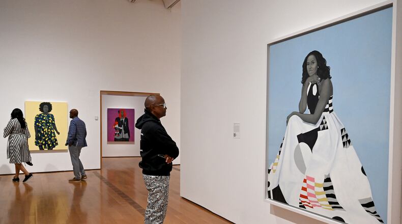A visitor looks at Amy Sherald's “Michelle Obama” in the “American Sublime” exhibition at the High Museum of Art on Friday, May 15, 2026, in Atlanta. Obama has spent years being subjected to racist and sexist attacks, guest columnist Tymia Ballard writes. (Hyosub Shin/AJC)
