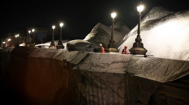 A worker monitors the inflation of "The Pont Neuf Cave" by French street artist JR on the Pont Neuf bridge in Paris on Wednesday, May 20, 2026, before its free public opening from June 6 to 28. (AP Photo/Thomas Padilla)