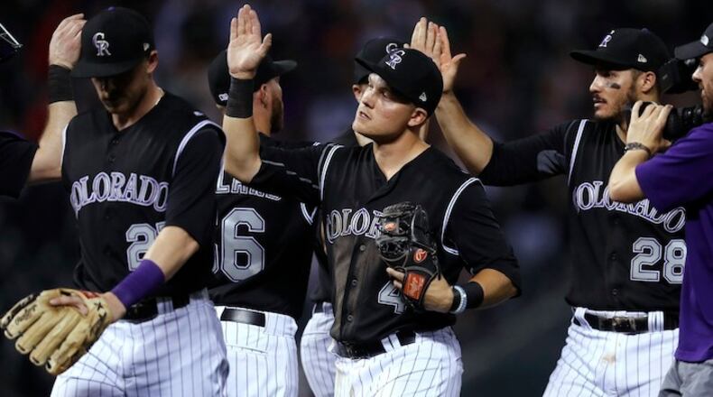 Colorado Rockies shortstop Pat Valaika, center, is congratulated by teammates after retiring the Cincinnati Reds in the ninth inning of a baseball game Wednesday, July 5, 2017, in Denver. The Rockies won 5-3. (AP Photo/David Zalubowski)