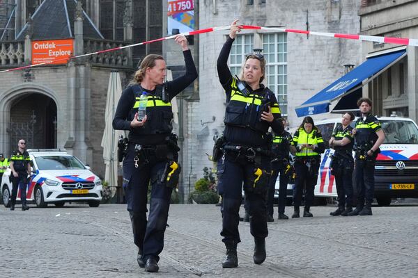 Police officers walk under the tape of a cordoned off area after a stabbing near Dam Square in central Amsterdam, Thursday, March 27, 2025. (AP Photo/Peter Delong)