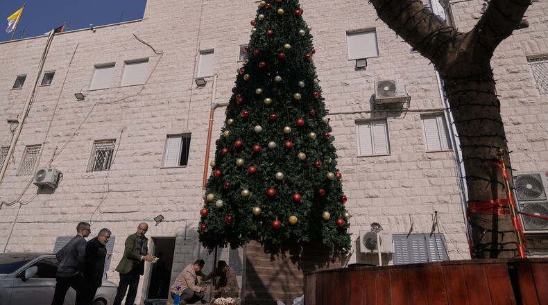 Palestinian parishioners check a recently installed Christmas tree after the previous one was destroyed at the Holy Redeemer Latin Church in the West Bank town of Jenin, Tuesday, Dec. 23, 2025. (AP Photo/Majdi Mohammed)