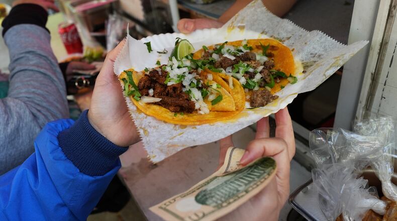 A bicyclist receives food from a street vendor Yulisa Robles, right, at Gage Park during Street Vendor Bike Tour Series, in Chicago, Sunday, Nov. 2, 2025. (AP Photo/Nam Y. Huh)