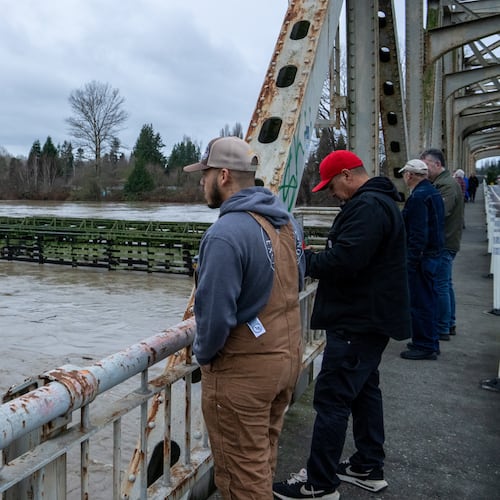 People stand on a bridge over the Skagit River in Lyman, Wash., Thursday, Dec. 11, 2025. (AP Photo/Stephen Brashear)