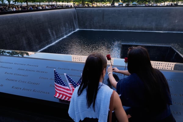 Sarah (left) and Ainsley Jurccak place a flower in the name of a relative during a ceremony to mark the 24th anniversary of the 9/11 attacks, Thursday, Sept. 11, 2025, in New York. (Seth Wenig/AP)