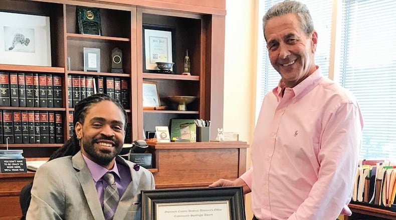 Arquevious “Que” Crane receiving the “community spotlight” award from Gwinnett County District Attorney Danny Porter. Employees of Porter’s office are now raising money to help Crane, a quadriplegic who is a motivational speaker, replace his aging van. VIA GWINNETT DISTRICT ATTORNEY’S OFFICE