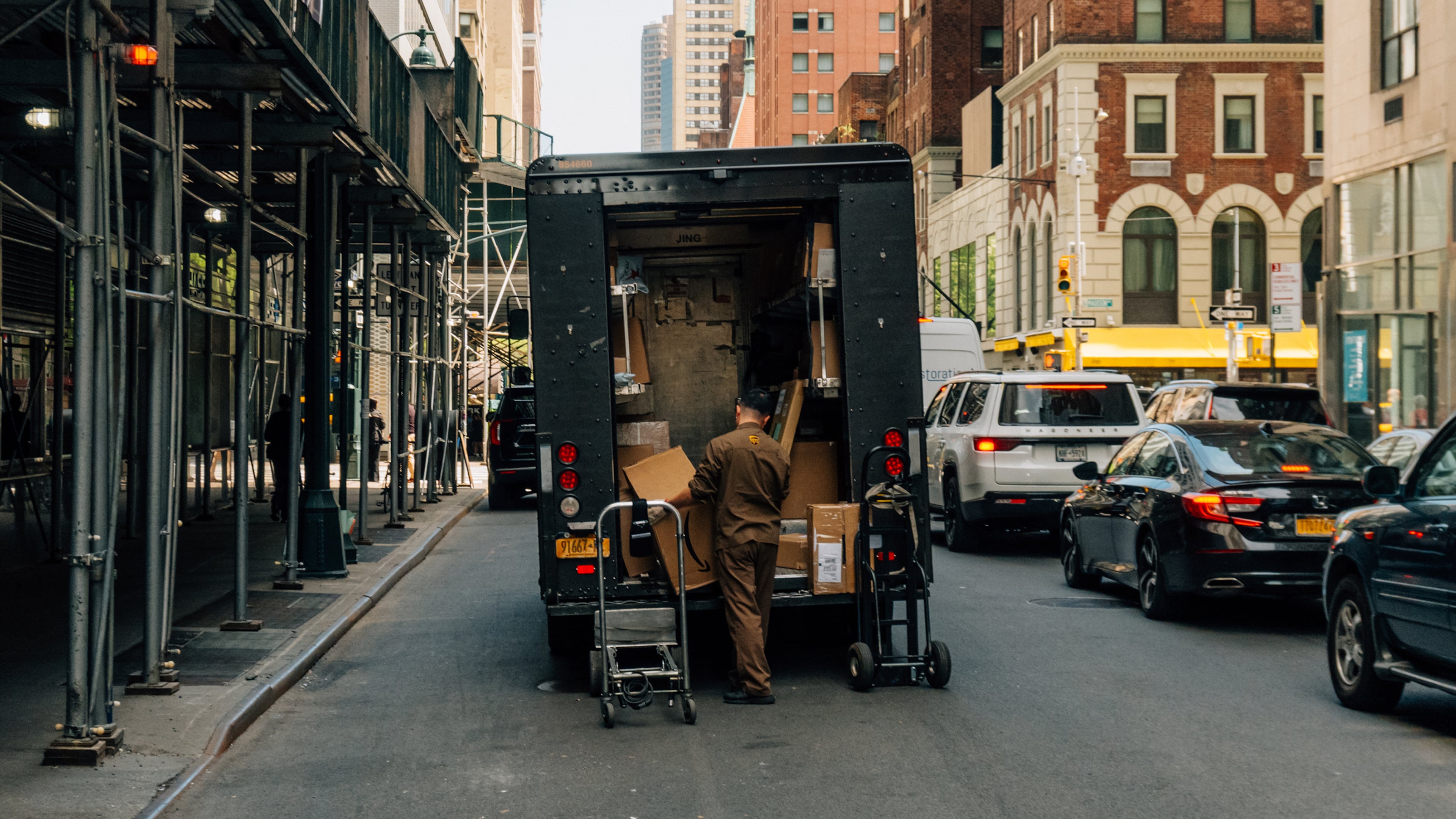 A UPS driver retrieves boxes from the back of his truck, in New York, April 29, 2025. Global shippers like Sandy Springs-based UPS have been left scrambling to adjust in real time to the fast-changing tariff landscape. (DeSean McClinton-Holland/The New York Times)