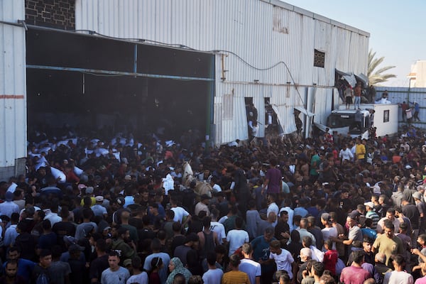 Palestinians storming a U.N. World Food Program warehouse and carry bags of flour in Zawaida, Central Gaza Strip, on Wednesday, May 28, 2025. (AP Photo/Abdel Kareem Hana)