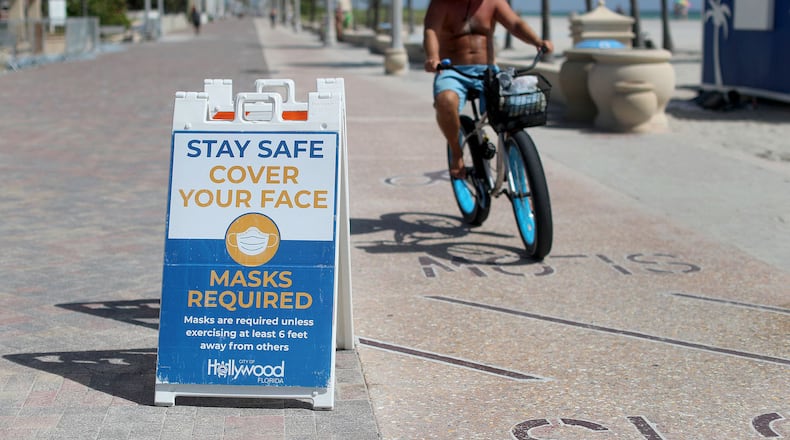 Signs posted along the broadwalk on the beach in Hollywood Florida advocate for people to wear a mask unless exercising 6 feet away from others in September 2020. (Mike Stocker/South Florida Sun Sentinel/TNS)