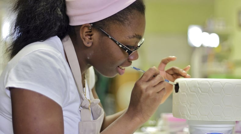 JuShawn Carter paints a cake she is preparing for a New York gala. The finished cake will have a soccer ball motif. Carter was 14 when she started her own business, Cakesbyfourteen. Now 17, the Atlanta high school student will be honored April 23 for her business acumen at the 25th Anniversary Network for Teaching Entrepreneurship Gala at the Waldorf Astoria Hotel in New York. She is the only student representing Youth Entrepreneurs Georgia.