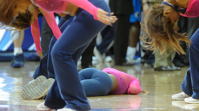 An Atlanta Hawks cheerleader lays on the ground as fellow cheerleaders continue to perform during a dance routine in which she hit the floor during the second half of a game between the Hawks and Mavericks at Philips Arena.