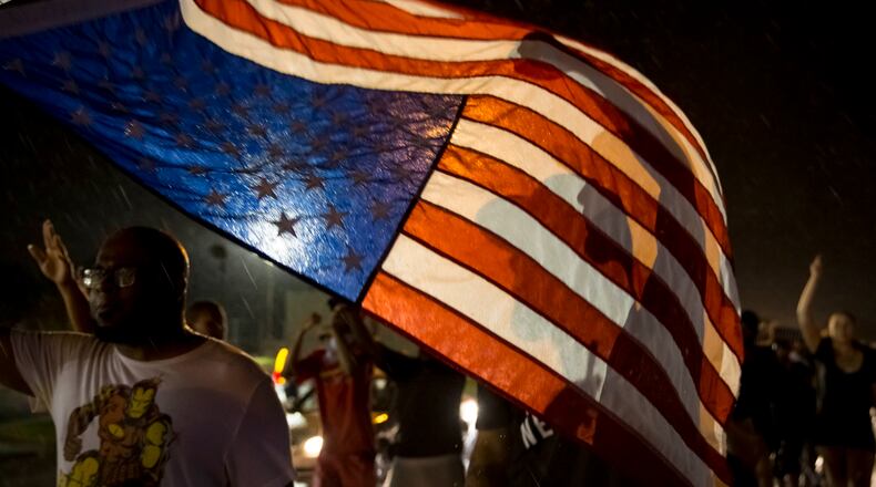 Protesters march down West Florissant Avenue on the anniversary of the fatal shooting of Michael Brown by a police officer in Ferguson, Mo., Aug. 9, 2015. A day of peaceful protest commemorating the killing of an unarmed black teenager by a white police officer one year ago ended in gunfire late Sunday. A St. Louis County police officer was involved in the shooting, the department said. (Whitney Curtis/The New York Times)