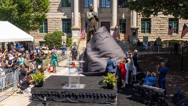 Dignitaries pull the cover off the statue during the unveiling ceremony honoring the late Congressman John Lewis in Decatur on Saturday, Aug 24, 2024.  (Steve Schaefer/AJC)
