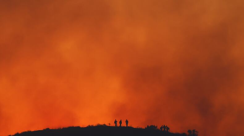 FILE - Firefighters are silhouetted amid an operation to control the Sandy Fire, May 19, 2026, in Simi Valley, Calif. (AP Photo/Caroline Brehman, File)