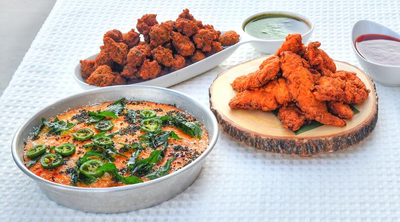 Chef Farhan Momin's dishes include Khaman Cornbread (lower left), Black-Eyed Pea Vada (upper left), Tandoori Fried Chicken (center) and Crispy Black-Eyed Pea Chaat (far right). Momin, an Atlanta dentist who also owns a restaurant that is part of his family's halal butcher shop in Suwanee, was a contestant in Season 9 of “MasterChef.” (Styling by chef Farhan Momin / Chris Hunt for the AJC)