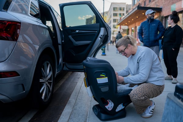 Elizabeth Mahon, owner of the baby store Three Littles, installs a new car seat for customers who made the purchase ahead of tarriff-driven price increases, at the Union Market location in Washington, on Wednesday, April 16, 2025. (AP Photo/Nathan Howard)