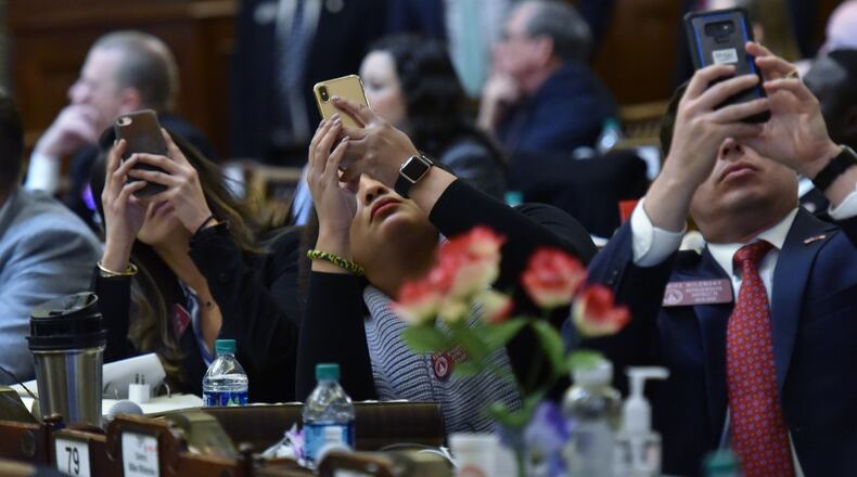 Reps. (from left) Bee Nguyen, Renitta Shannon and Mike Wilensky take pictures of the result as they vote on HB 481, which would outlaw abortions once a doctor can detect a heartbeat in the womb, in the House Chambers during Crossover day at the Capitol on Thursday, March 7, 2019. HYOSUB SHIN / HSHIN@AJC.COM